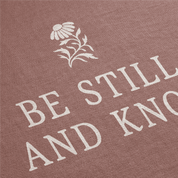 Text 'Be Still and Know' with a flower design on a brown background