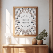 Framed artwork with motivational quote on a wall above a wooden console table with decorative vases and plants.