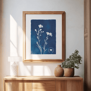 Framed botanical print on a wall above a wooden console table with decorative vases and plants.