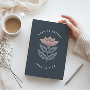 Notebook with floral design and text on a white surface with a cup of coffee and pen.