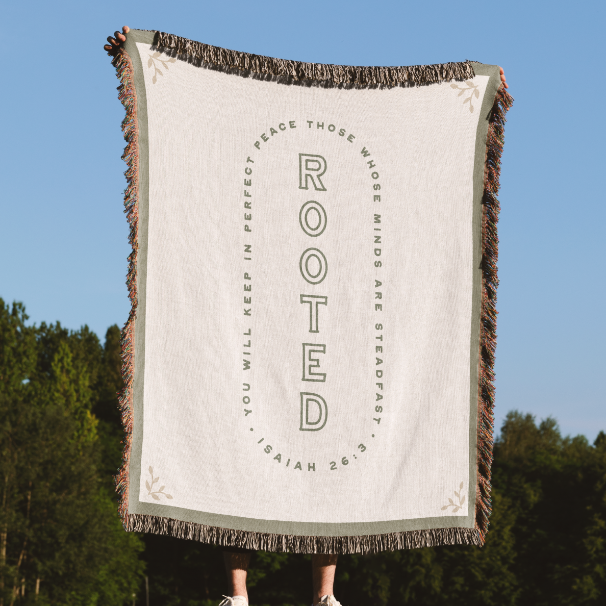 Blanket with text design held up against a natural background