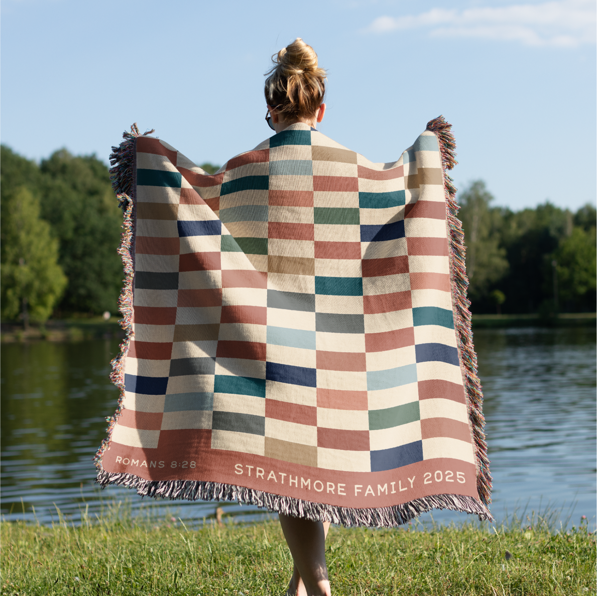 Person holding a striped blanket with text by a lake