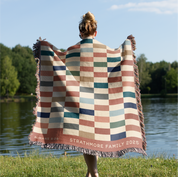 Person holding a striped blanket with text by a lake