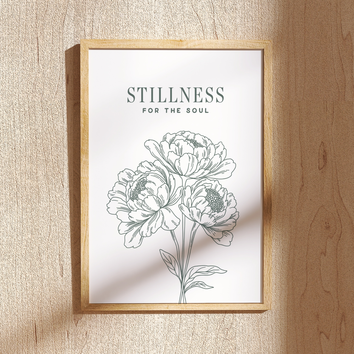 Framed artwork with floral design and text 'Stillness for the Soul' on a textured wall.