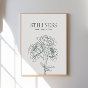 Framed artwork with floral design and 'Stillness for the Soul' text on a white wall.