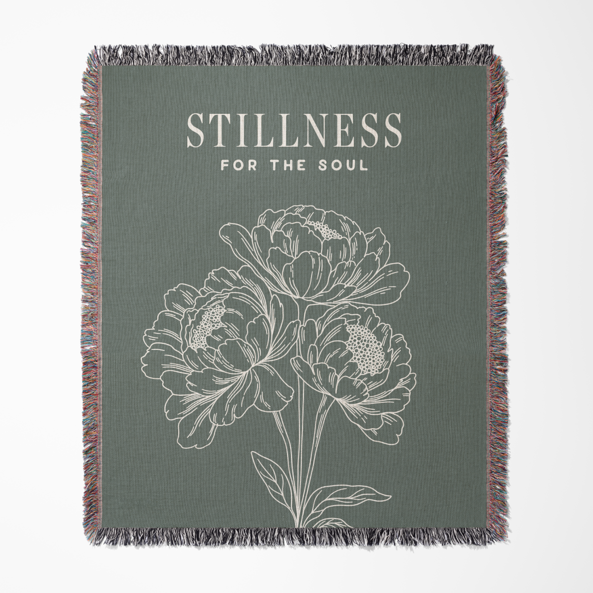 Blanket with floral design and 'Stillness for the Soul' text on a green background