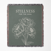 Blanket with floral design and 'Stillness for the Soul' text on a green background