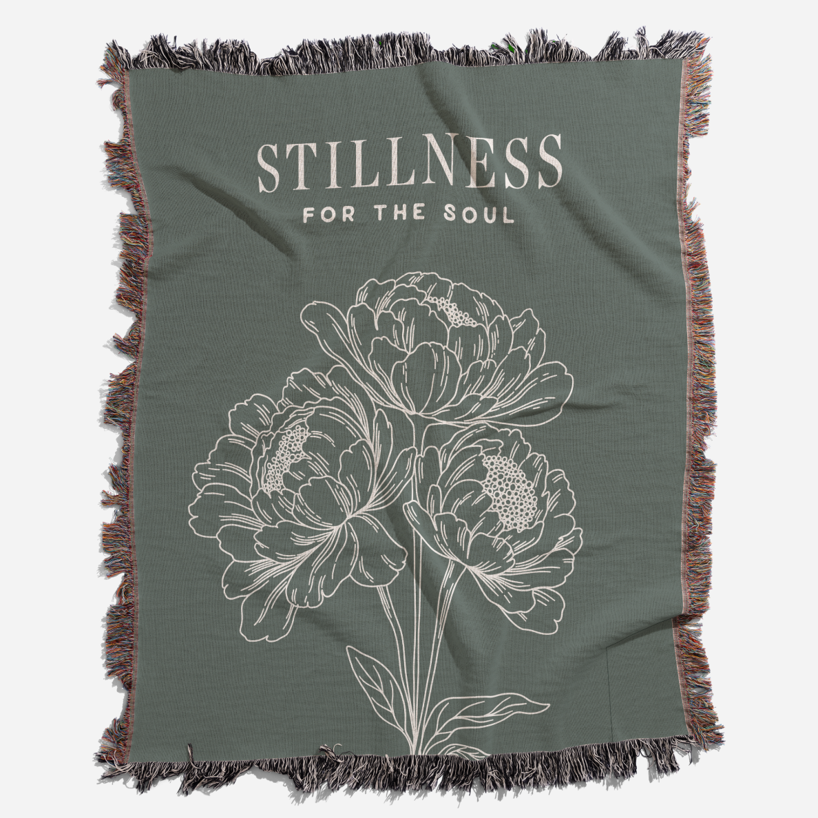 Green throw blanket with floral design and 'Stillness for the Soul' text on a white background