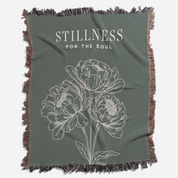 Green throw blanket with floral design and 'Stillness for the Soul' text on a white background