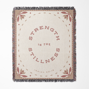 Blanket with 'Strength in the Stillness' text and floral patterns on a beige background