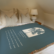Bed with green blanket featuring a tree design and text, in a bedroom setting.