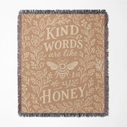 Warm-toned woven blanket with the phrase “Kind words are like honey,” floral accents, and a honey bee; 100% cotton with fringe, perfect for Christian gifting and home decor.