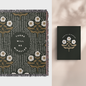 Floral-patterned blanket and matching notebook with 'There will be miracles' text on a neutral background