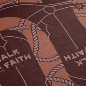 Close-up of a fabric with a design of boots and 'Walk by Faith' text on a brown background.