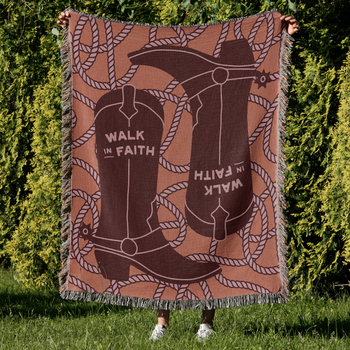Blanket with cowboy boots and 'Walk in Faith' text held by a person outdoors.