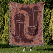 Blanket with cowboy boots and 'Walk in Faith' text held by a person outdoors.