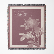 Blanket with floral design and 'Wrapped in Peace' text on a maroon background