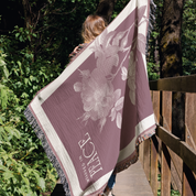 Person holding a floral-patterned towel with 'Peace' text in a forest setting